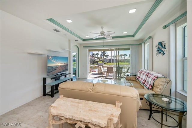 tiled living room with crown molding, ceiling fan, and a tray ceiling