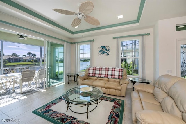 living room with a water view, ceiling fan, and a raised ceiling