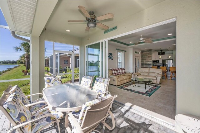 sunroom featuring a water view and ceiling fan