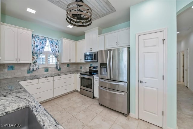 kitchen with light stone countertops, white cabinetry, appliances with stainless steel finishes, and tasteful backsplash