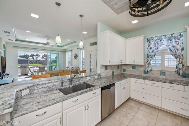 kitchen with sink, dishwasher, white cabinetry, a tray ceiling, and light stone countertops