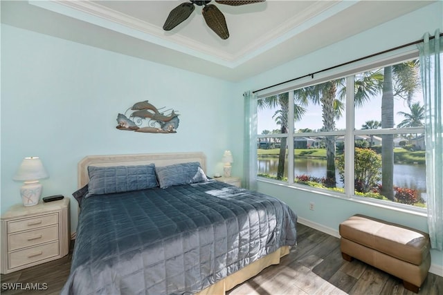 bedroom featuring crown molding, ceiling fan, dark hardwood / wood-style floors, a water view, and a raised ceiling