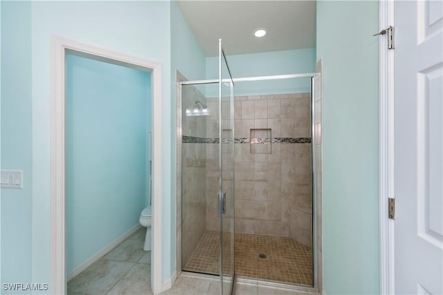 bathroom with tile patterned floors, toilet, and a shower with door