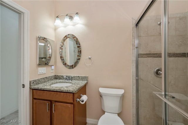 bathroom with vanity, toilet, and a shower with door