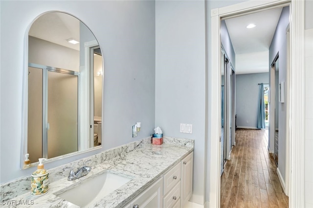 bathroom featuring vanity, wood-type flooring, toilet, and walk in shower