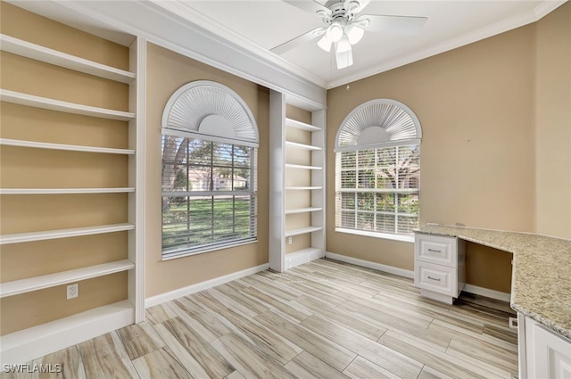 unfurnished office with crown molding, light hardwood / wood-style flooring, built in features, ceiling fan, and built in desk