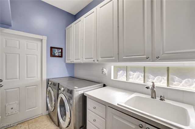 clothes washing area with cabinets, washer and clothes dryer, sink, and light tile patterned floors