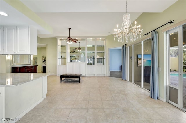 interior space with white cabinetry, light stone counters, decorative light fixtures, light tile patterned floors, and ceiling fan with notable chandelier