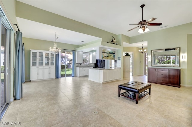 unfurnished living room featuring light tile patterned flooring and ceiling fan with notable chandelier