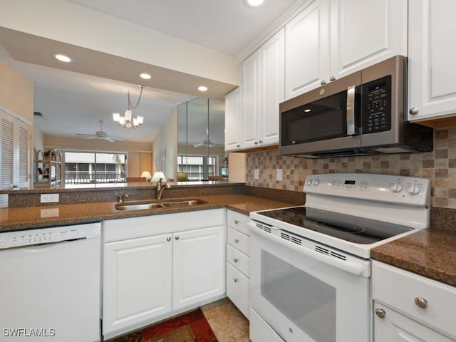 kitchen with sink, white appliances, backsplash, white cabinets, and ceiling fan with notable chandelier