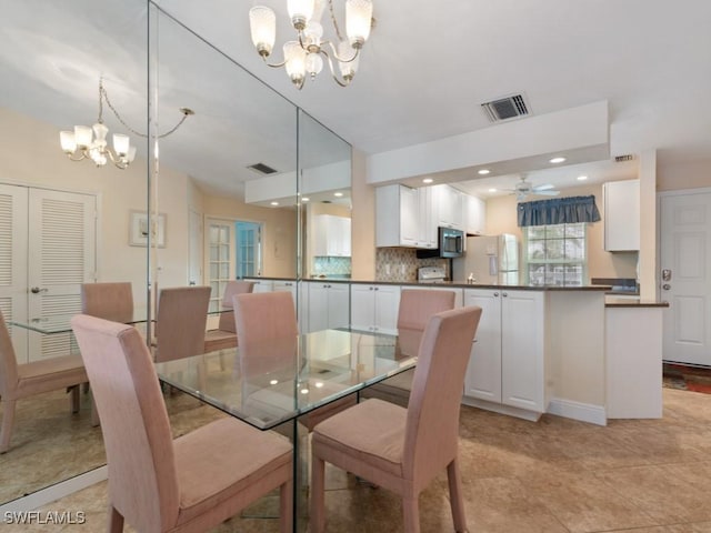 dining space featuring ceiling fan with notable chandelier