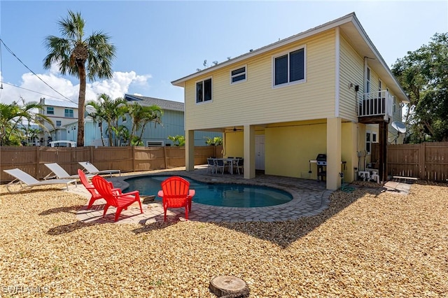 rear view of house with a fenced in pool, a balcony, and a patio area