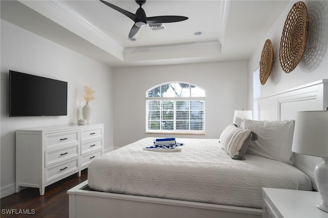 bedroom featuring dark hardwood / wood-style flooring, a tray ceiling, ornamental molding, and ceiling fan