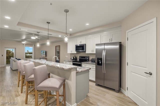 kitchen with white cabinetry, stainless steel appliances, an island with sink, and a breakfast bar area