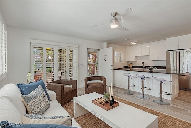 living room featuring sink, ceiling fan, and light hardwood / wood-style flooring