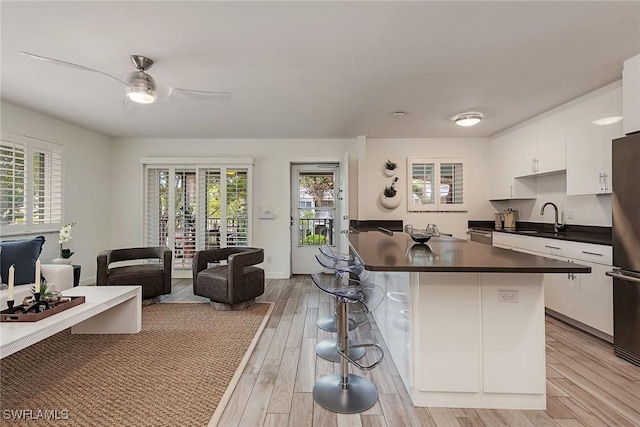 kitchen with white cabinetry, sink, ceiling fan, and light hardwood / wood-style flooring