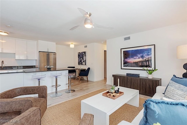 living room with sink, ceiling fan, and light hardwood / wood-style flooring