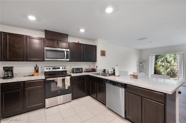 kitchen with sink, light tile patterned floors, kitchen peninsula, stainless steel appliances, and dark brown cabinets