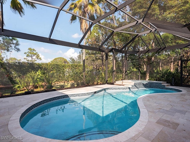 view of pool with an in ground hot tub, a patio area, and glass enclosure