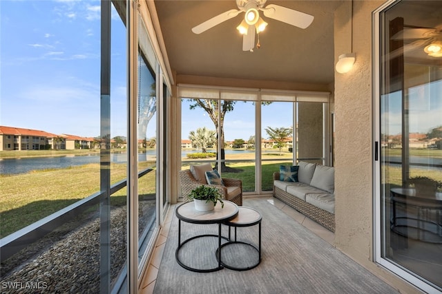 sunroom featuring ceiling fan and a water view