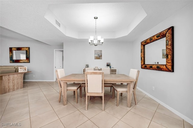 tiled dining space with an inviting chandelier, a tray ceiling, and a textured ceiling