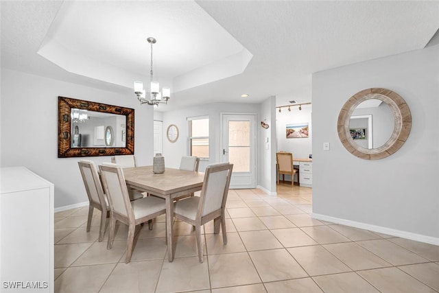 dining area featuring an inviting chandelier, a textured ceiling, light tile patterned floors, a tray ceiling, and washer / clothes dryer