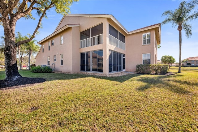 back of property with a lawn and a sunroom