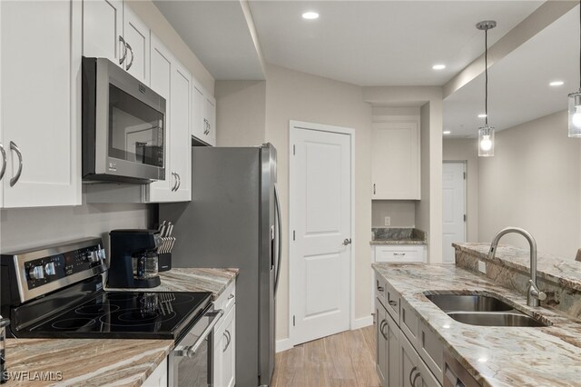 kitchen with light stone counters, stainless steel appliances, sink, and white cabinets