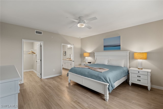 bedroom with ensuite bathroom, a walk in closet, light hardwood / wood-style flooring, a closet, and ceiling fan