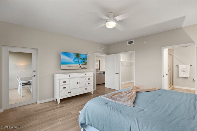 bedroom with ceiling fan, ensuite bath, a spacious closet, and light wood-type flooring