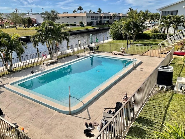 view of pool featuring a water view, a lawn, and a patio area