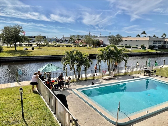 view of pool featuring a yard, a patio area, and a water view