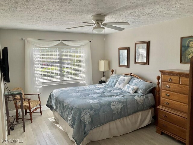 bedroom with ceiling fan, a textured ceiling, and light wood-type flooring