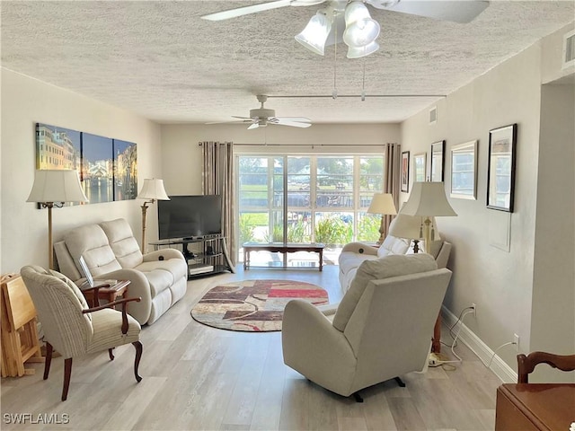 living room featuring ceiling fan, a textured ceiling, and light wood-type flooring