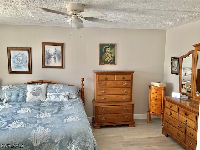 bedroom with ceiling fan, a textured ceiling, and light hardwood / wood-style flooring