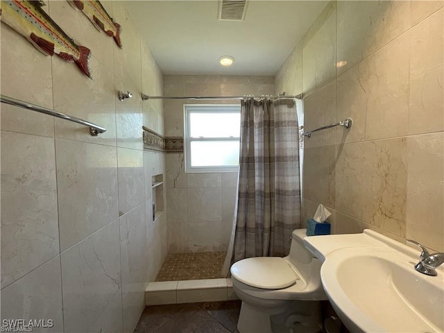 bathroom featuring toilet, sink, tile walls, and walk in shower