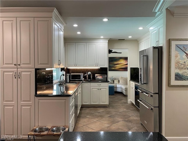 kitchen featuring high quality fridge, sink, white cabinets, decorative backsplash, and dark tile patterned floors