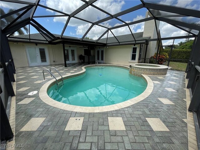 view of pool with an in ground hot tub, a lanai, a patio area, and french doors