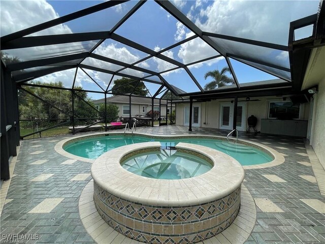 view of pool with an in ground hot tub, glass enclosure, and a patio area