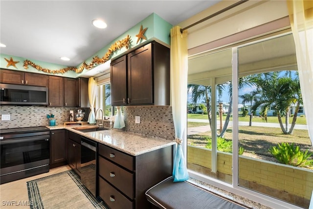 kitchen featuring light tile patterned flooring, sink, tasteful backsplash, dark brown cabinets, and appliances with stainless steel finishes