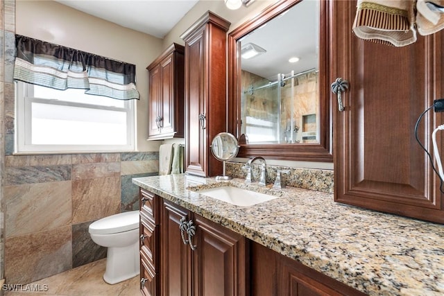 bathroom featuring tile patterned floors, toilet, a shower, tile walls, and vanity