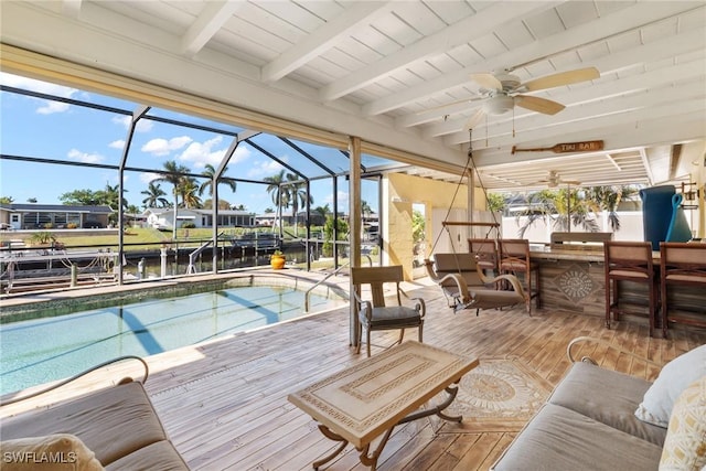 view of swimming pool with a lanai, a water view, ceiling fan, and a bar