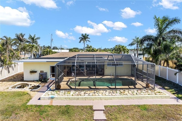 rear view of house with a fenced in pool, a yard, glass enclosure, and a patio area