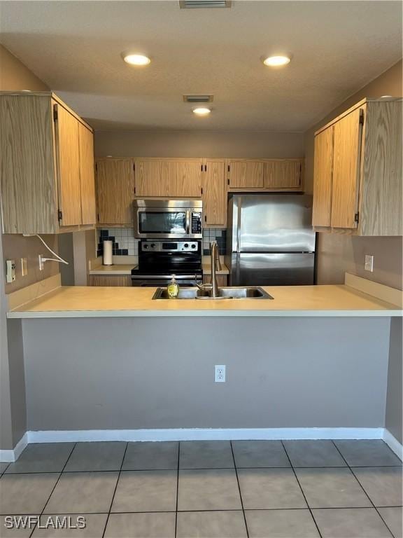 kitchen featuring tasteful backsplash, sink, light tile patterned floors, kitchen peninsula, and stainless steel appliances