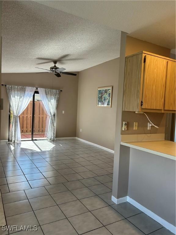 interior space featuring light tile patterned floors, a textured ceiling, ceiling fan, and kitchen peninsula