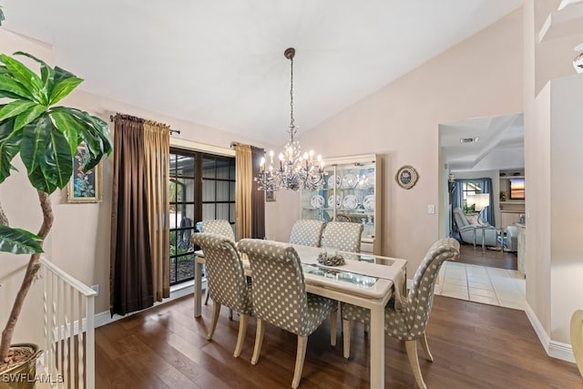 dining room with dark wood-type flooring, high vaulted ceiling, and an inviting chandelier