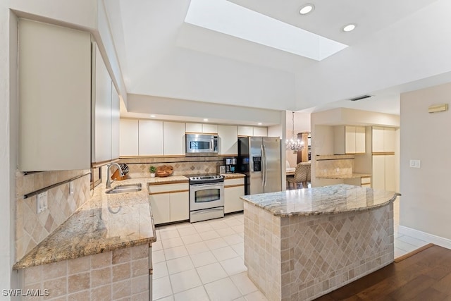 kitchen featuring sink, light stone counters, white cabinetry, stainless steel appliances, and backsplash