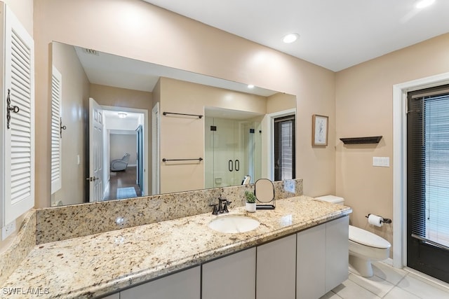 bathroom with tile patterned floors, vanity, toilet, and a shower with shower door