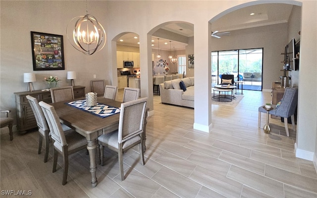 dining room featuring ceiling fan with notable chandelier and a high ceiling