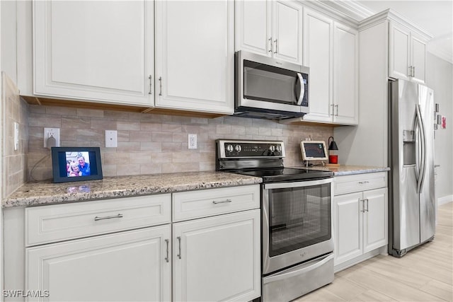 kitchen featuring appliances with stainless steel finishes, white cabinetry, backsplash, light stone counters, and light hardwood / wood-style floors